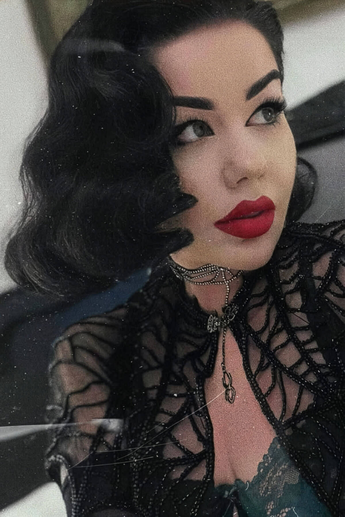 Woman wearing a black lace top with red lipstick and dark hair. Black lacefront wig, pinup/vintage style, mid length with finger waves: Lilith black 1B gothic 