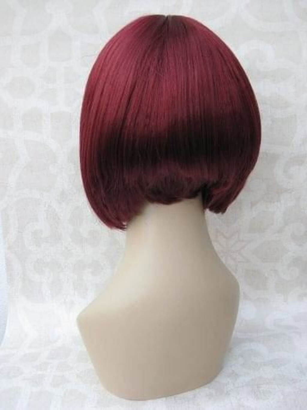 Red wig on a mannequin head against a white background. Red inverted bob wig, short and chic: Flavia