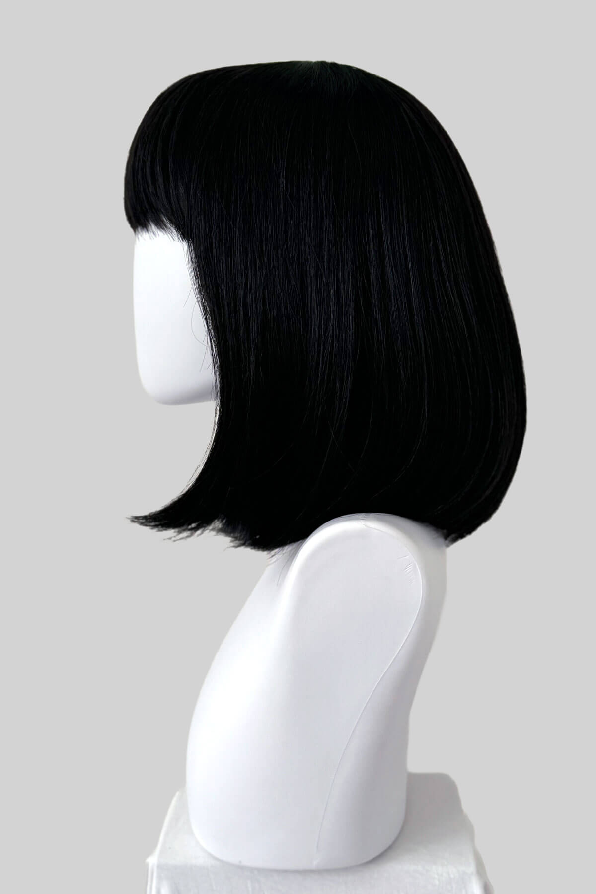 Black bob wig on a white mannequin head against a gray background. Black long bob wig, shoulder length: Evie