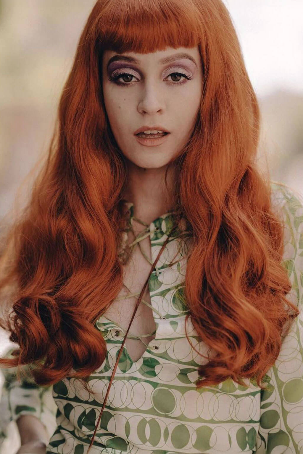 Person with long wavy red hair wearing a patterned dress. Long ginger wig with loose waves and curls: Ginger