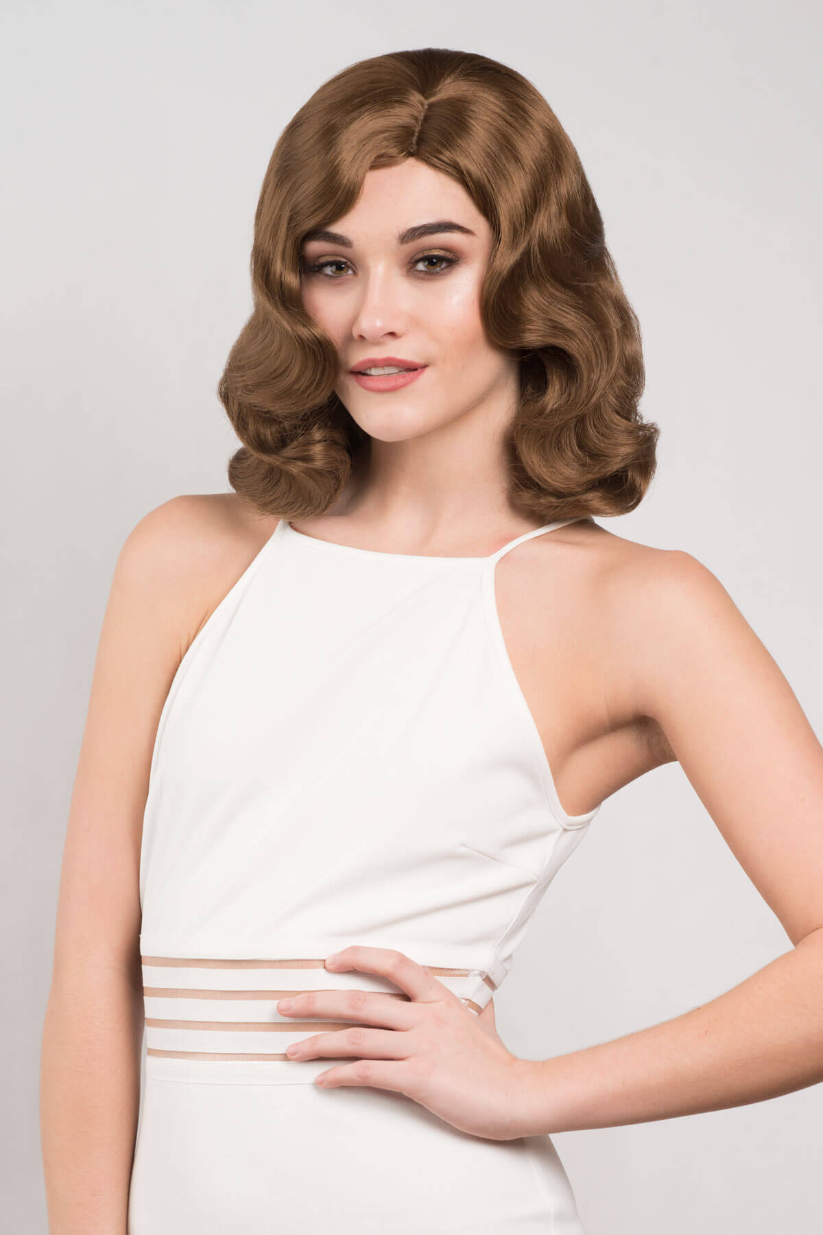 Woman wearing a vintage-style wig with a plain background. Brown 1940s pinup style wig, with finger waves: Honey light brown 12