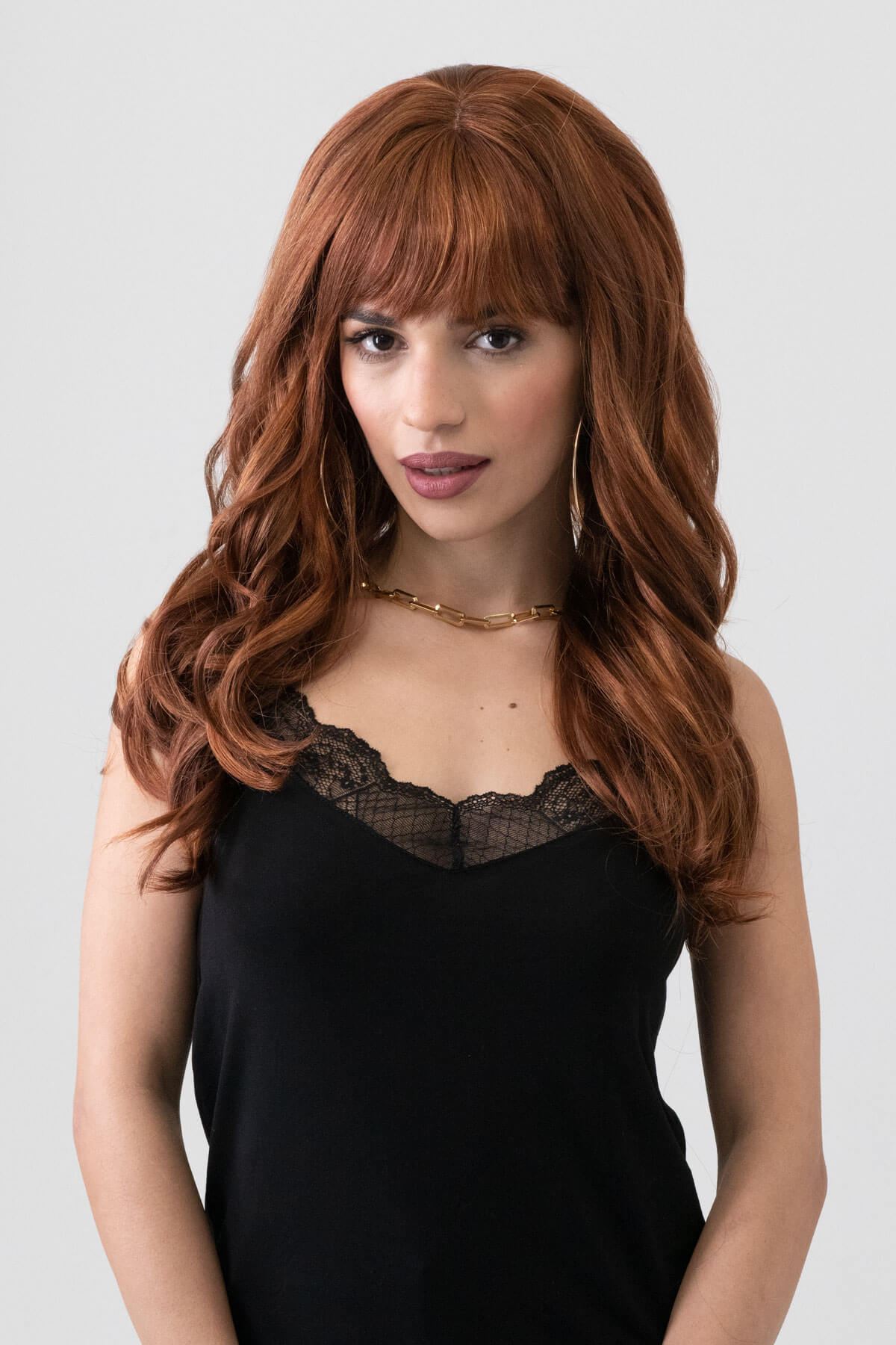 Woman with long brown wig wearing a black dress against a white background. Red auburn & blonde wig with long cascading waves: Floriana
