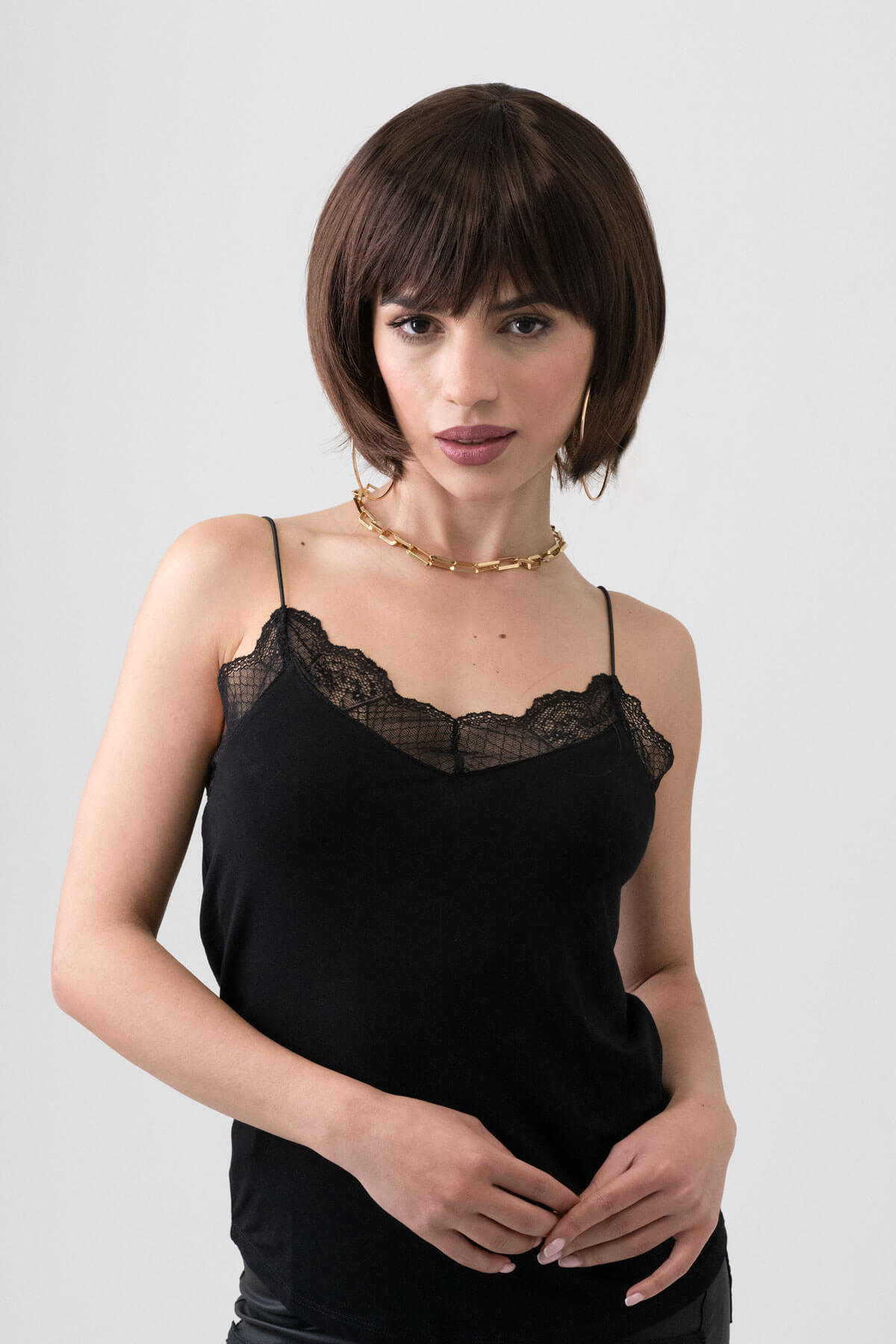 Woman wearing a black lace camisole against a plain background. Dark brown pixie cut wig with reddish brown lowlights: Cierra
