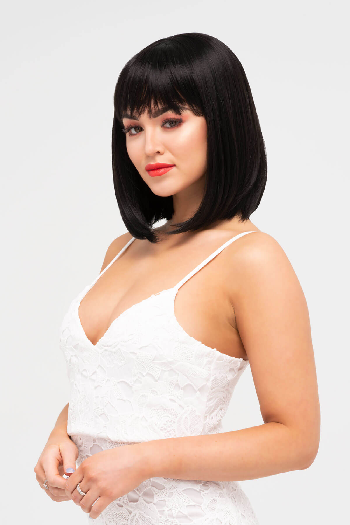 Woman with a stylish bob haircut wearing a white dress on a light background. Black long bob wig, shoulder length: Evie