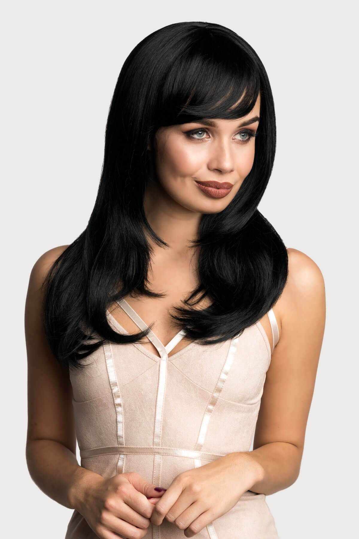 Woman with long black hair wearing a beige dress on a white background. Long black wig, face frame style with full, sweeping fringe: Corina