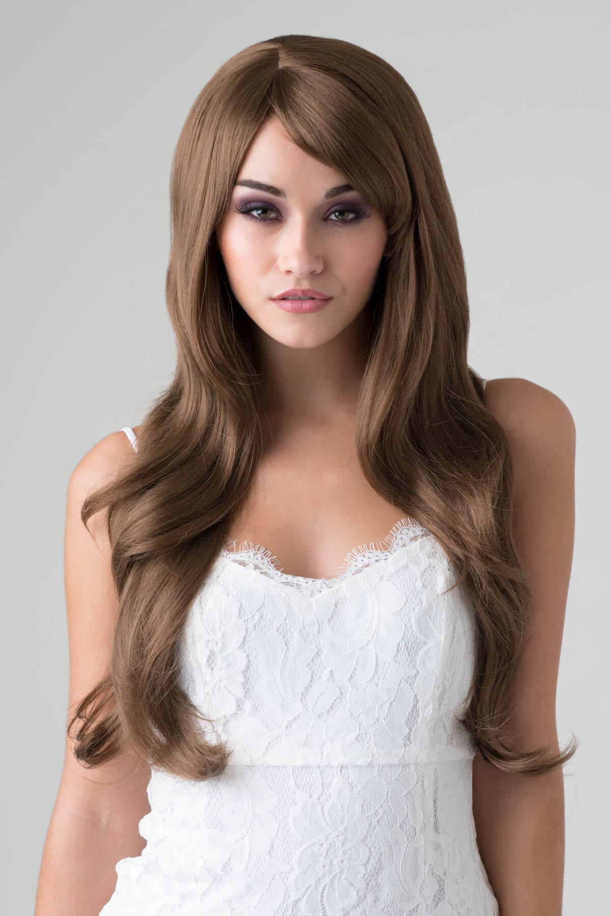 Woman wearing a long brown wig against a plain background. Long brown wig with loose waves: Mandy light chocolate brown 12