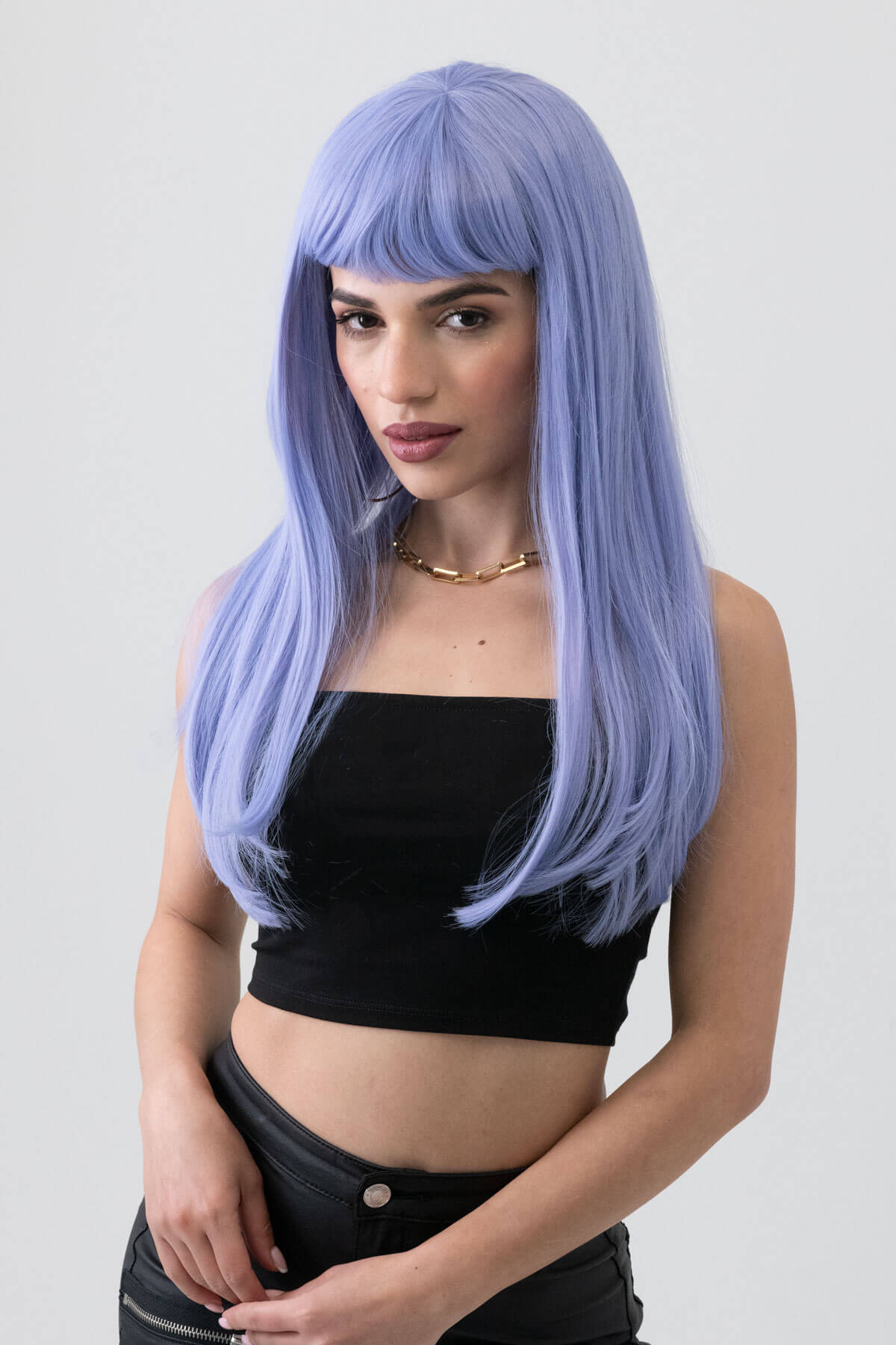 Woman with long blue wig wearing a black top against a plain background. Long blue wig with short, straight fringe: Alyssa