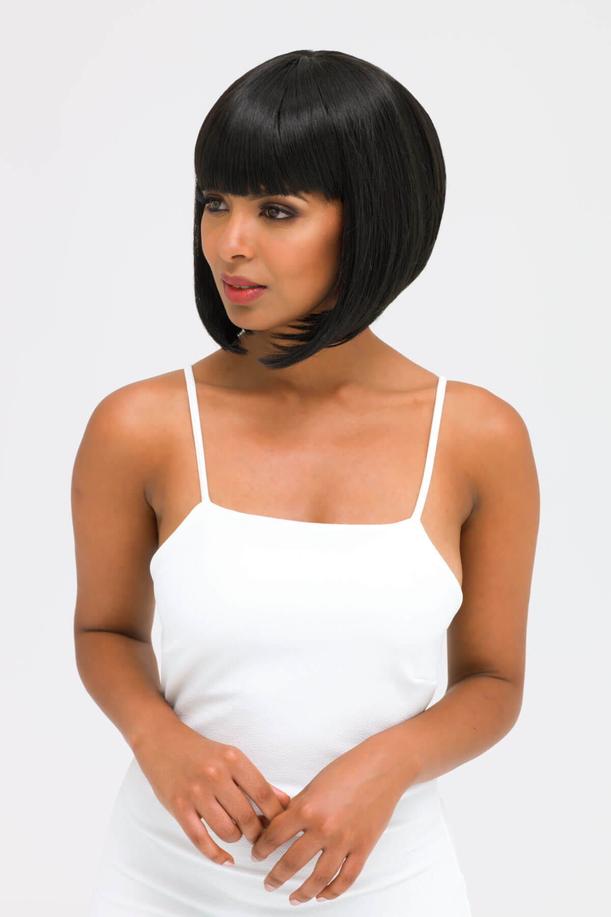 Woman wearing a white tank top with a plain background. Black inverted bob wig: Chloe