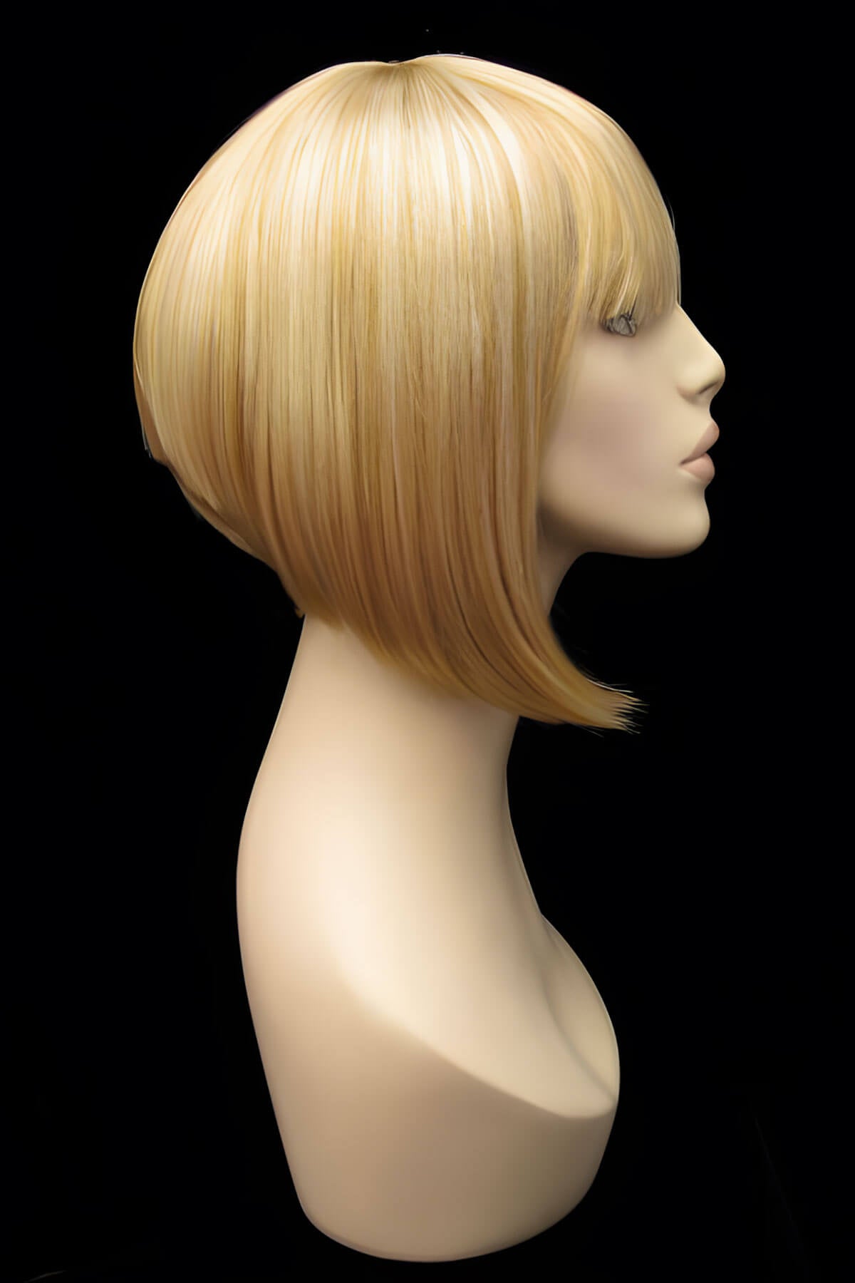 Blonde wig on a mannequin head against a black background.  Blonde inverted bob wig: Rhiannon honey blonde 24BH613