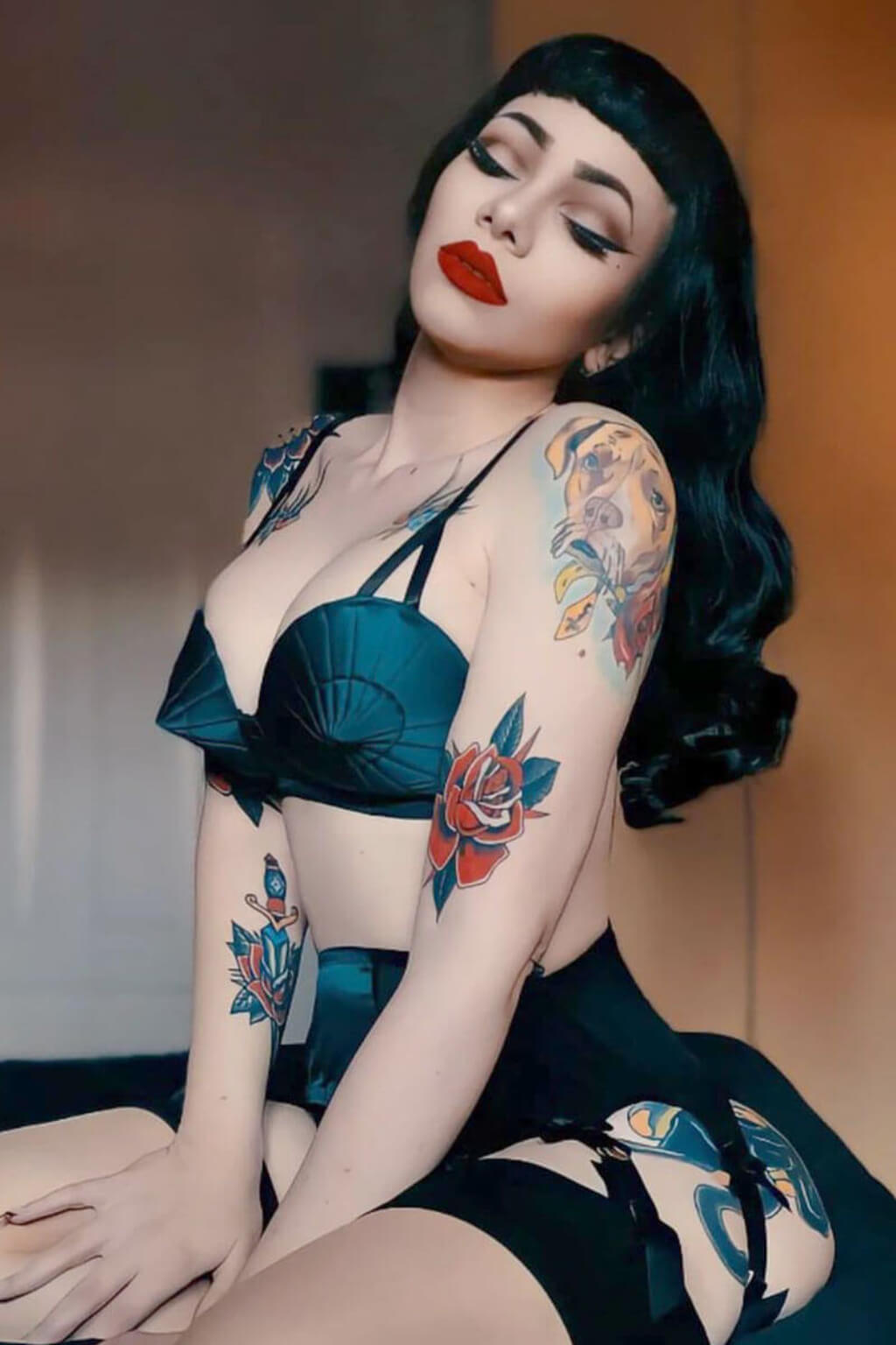 Woman with tattoos wearing a Black 1950s pinup style wig, curled with short fringe: Milena